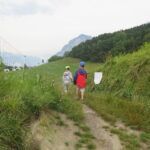 Zwei Kinder mit Schmetterlingsnetzen auf einem Weg, der durch Wiesen führt